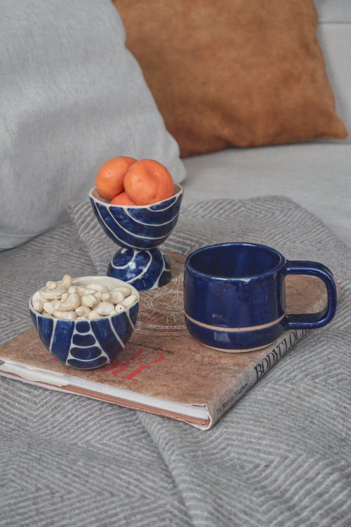 rankomis lipdytas mėlynas puodelis su ąselė